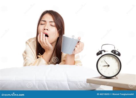 Asian Girl Wake Up Yawn With Alarm Clock And Coffee Cup Stock Image