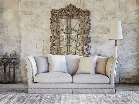 A Living Room With A Couch Lamp And Mirror On The Wall In Front Of It