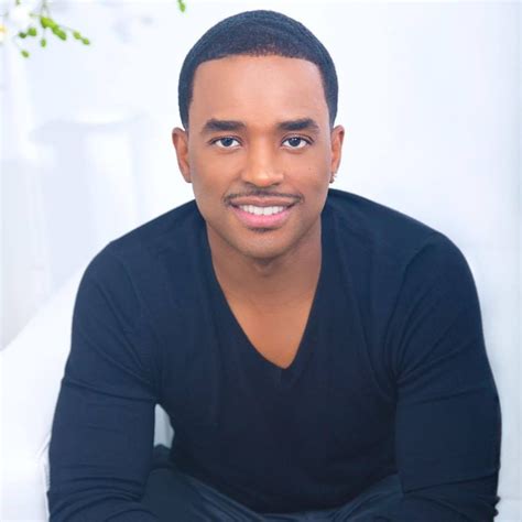 A Man Sitting On Top Of A White Couch Wearing A Black Shirt And Jeans