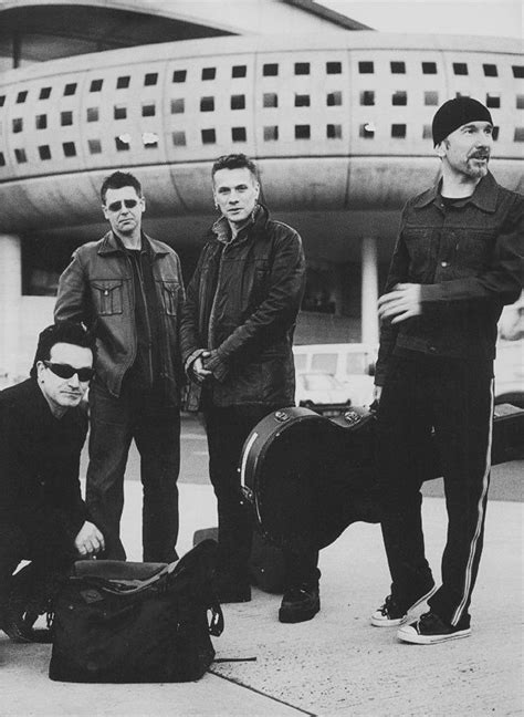 Three Men Standing Next To Each Other With Luggage On The Ground In