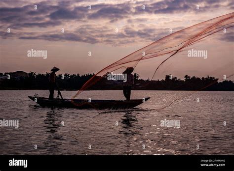 Vietnamese Fisherman Throwing A Net To Catch Food For The Village Stock