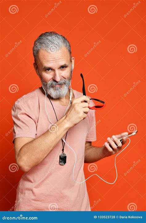 Senior Man Listening To Music On Headphones On Orange Background Stock