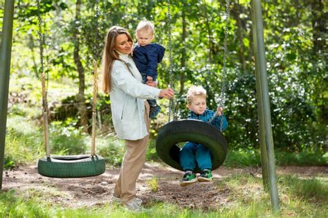 The Mother Is Swinging Her Children On The Swings Stock Photo Image