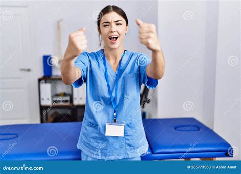 Young Hispanic Woman Wearing Physiotherapist Uniform Standing At Clinic Angry And Mad Raising