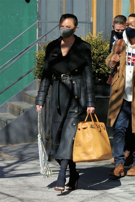 Chrissy Teigen In A Full Length Black Leather Coat And Open Toe High