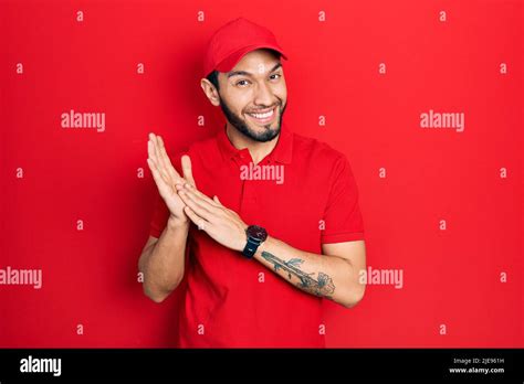 Hispanic Man With Beard Wearing Delivery Uniform And Cap Clapping And