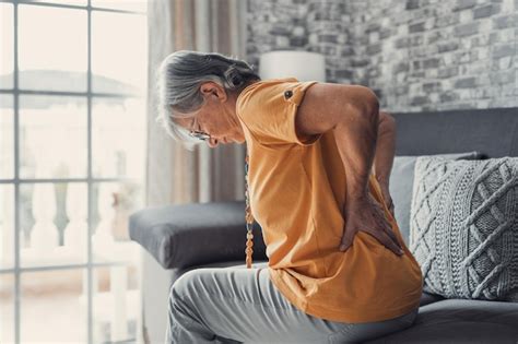 Premium Photo Unhappy Mature Woman Touching Back Feeling Pain Sitting On Couch In Living Room