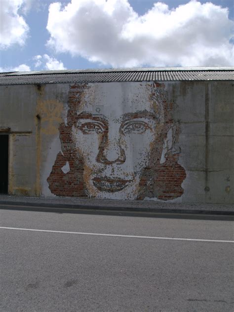 A Mural On The Side Of A Building With A Mans Face Painted On It