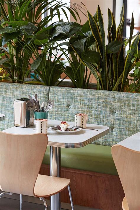 Two White Chairs Sitting At A Table With Food On It And Plants In The