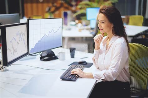 Confidient Professional Woman Sitting At Desk And Surrounded By Computers While Working At The