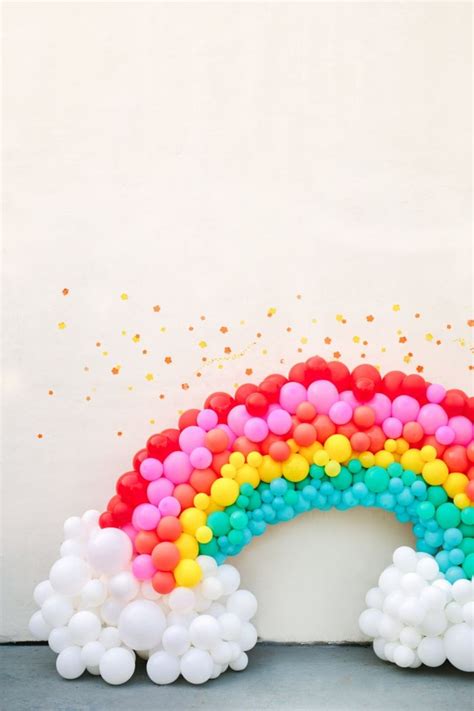 A Rainbow Shaped Balloon Arch In Front Of A White Wall