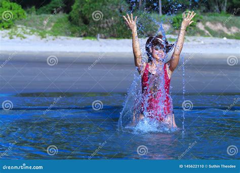 Woman With Bikini Crimson And Hat Play Water On Beach Stock Photo