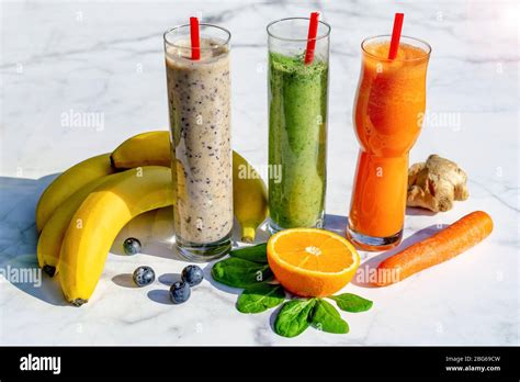 3 Different Kind Of Smoothies With Ingredients On Marble Table