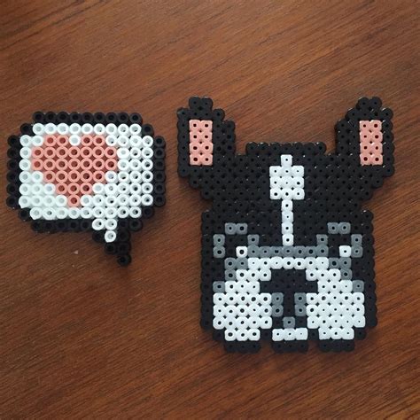 Two Pieces Of Bead Art Sitting On Top Of A Wooden Table