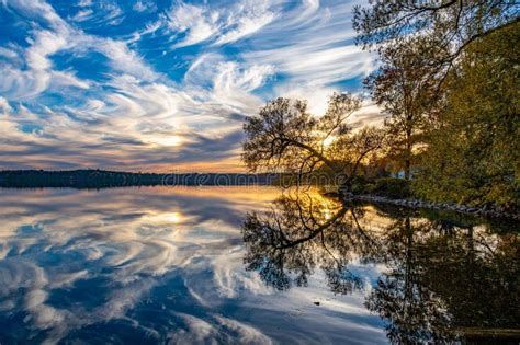 Serene Image Of A Breathtaking Sunset Over A Lake With Tall Majestic