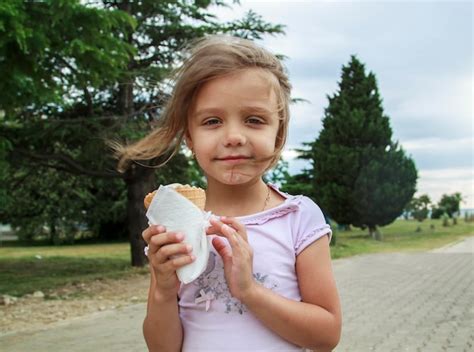 Premium Photo Portrait Of Cute Girl Holding Ice Cream Against Trees