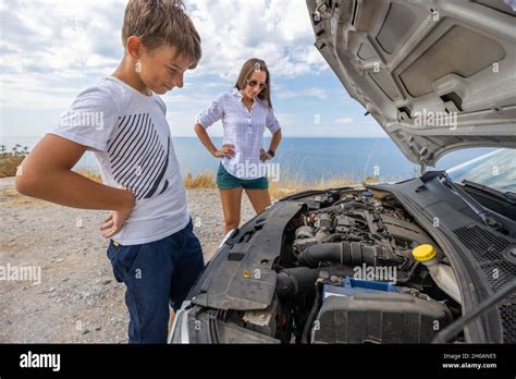Teenage Boy With His Mother Trying To Fix Broken Rent Car During Summer