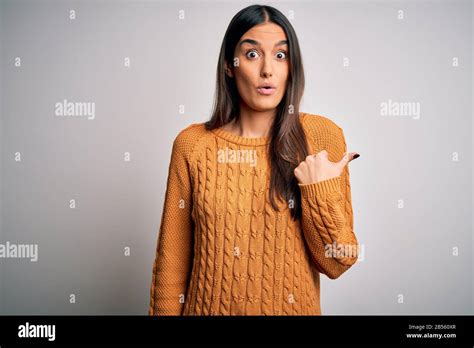 Jeune femme de la belle brunette portant un pull décontracté sur un fond blanc isolé Surpris de