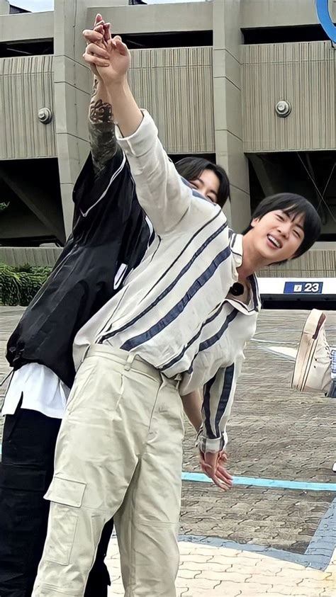 Two People Standing On Top Of A Skateboard