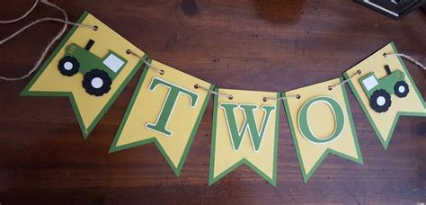 A Green And Yellow Banner That Says Two With A Tractor In The Middle On