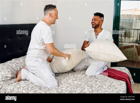 Playful Gay Couple Pillow Fighting In Bedroom At Home Stock Photo Alamy