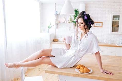 De Jonge Mooie Onbezorgde Vrouw Zit En Rust Op Lijst In Keuken Ochtend Het Brunette Met