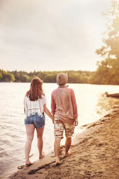 Junges Paar das Händchen haltend am Strand spazieren Lizenzfreies