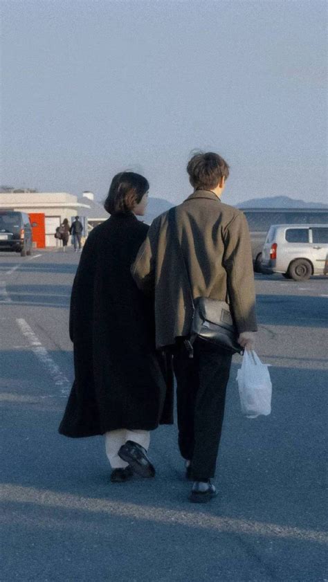 Two People Walking Down The Street Carrying Bags