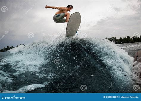 Sportive Man Skilfully Jumps Over Splashing Wave On Wakesurf Board