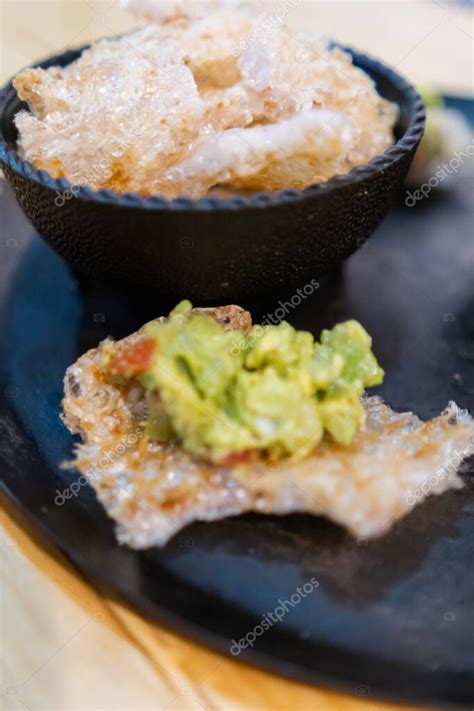 Corteza de cerdo con guacamole y tazón de cortezas de cerdo en el