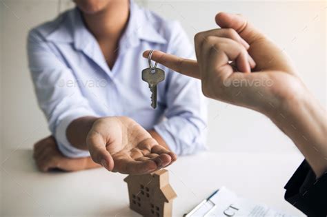 Hand Of Real Estate Agent Passes The Key To New Homeowners In Office With Buyer House Concept