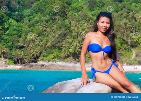 Vackra Bilder Av En Asiatisk Kvinnlig Modell I Blå Bikini Som Sitter På En Sten Och Slickar