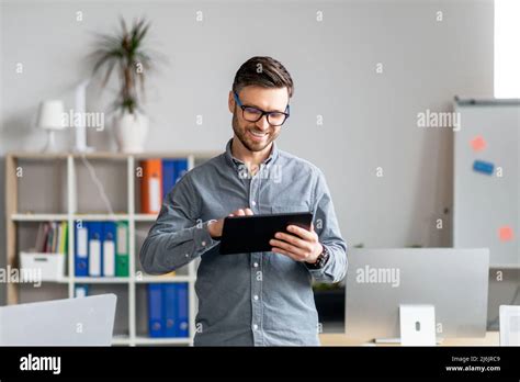 Portrait Of Cheerful Mature Businessman Using Computer Tablet In Office