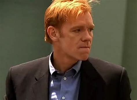 a man with red hair wearing a suit and blue shirt looking off to the side