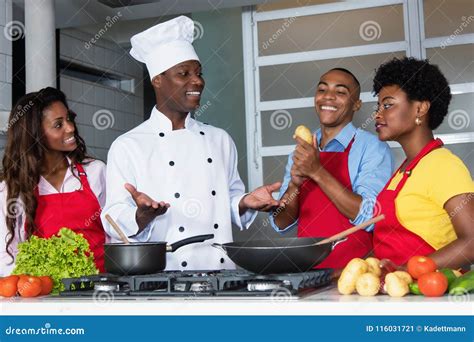 African American Chef Teaching Women And Men At Kitchen Stock Image