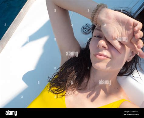 Young Woman In A Bright Yellow One Piece Swimsuit Sunbathing On The