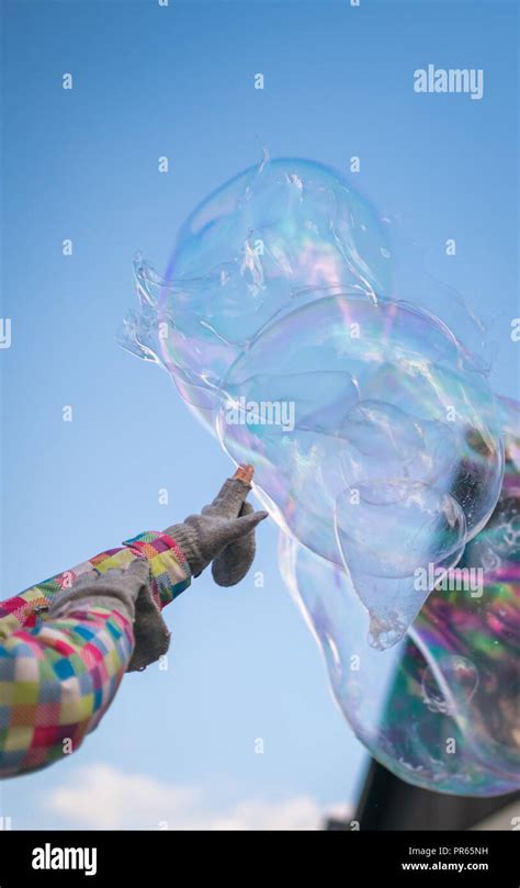 Girl Reaching Out Her Hand Trying To Touch The Giant Soap Bubbles