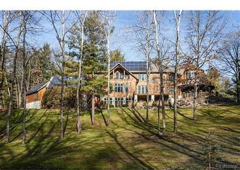 A Large House In The Woods With Lots Of Trees And Grass On Both Sides Of It