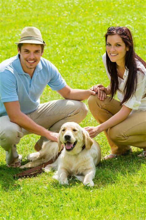 Pares Jovenes Sonrientes Que Mienten En Hierba Y El Abrazo De Un Perro