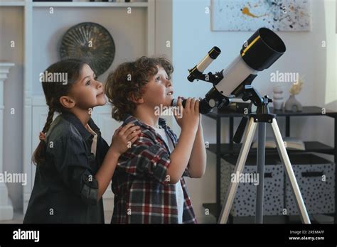 Cute little children using telescope to look at stars in room Stock ...