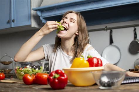 Young Girl Prepares A Vegetarian Salad In The Kitchen She Looks Into A