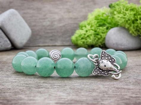 A Bracelet With Green Beads And An Elephant Head Charm On The Clasp