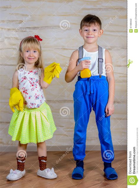 Menino E Menina Que Guardam Luvas E Pulverizador Da Limpeza Foto De