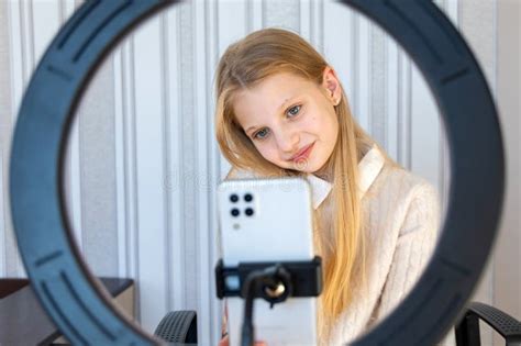 Blonde Girl Filming Content With Ring Light A Blonde Girl Is Focused On Her Smartphone As She
