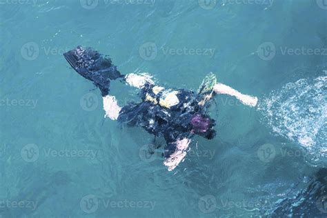 Top View Of Scuba Diver Swimming Under Water And Examines The Seabed