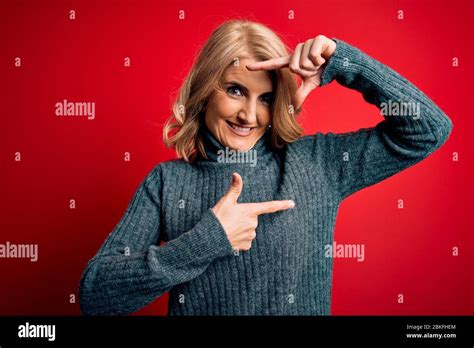 Middle Age Beautiful Blonde Woman Wearing Casual Turtleneck Sweater Over Red Background Smiling