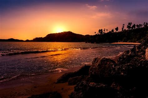 Premium Photo | A beach at sunset with a mountain in the background