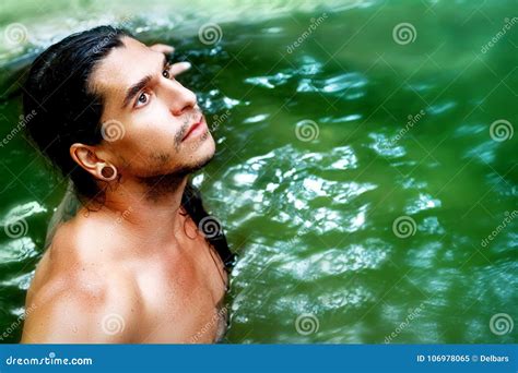 A Handsome Guy With Long Hair And Piercings On Waterfalls In A Rain