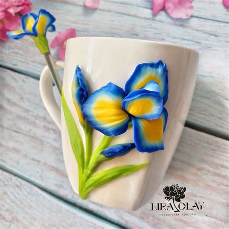a coffee cup decorated with blue and yellow flowers on top of a wooden ...