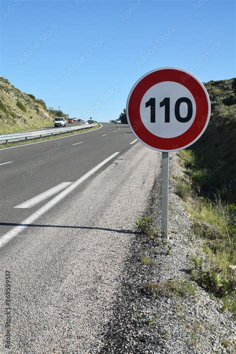 Panneau vitesse limitée à 110 au bord d une route à quatre voies Stock